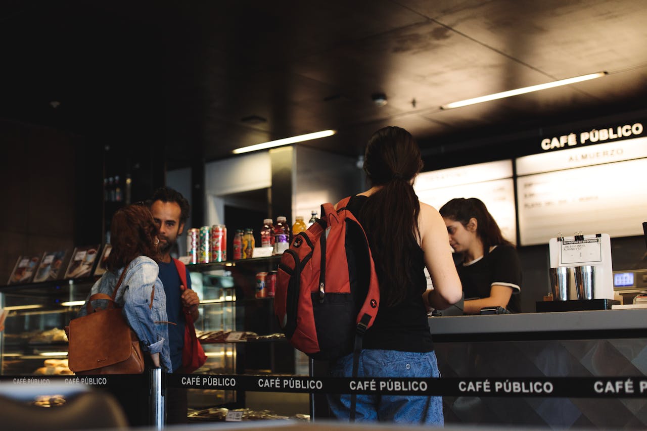 services-02 Young adults interacting at a modern café counter, ordering and conversing.