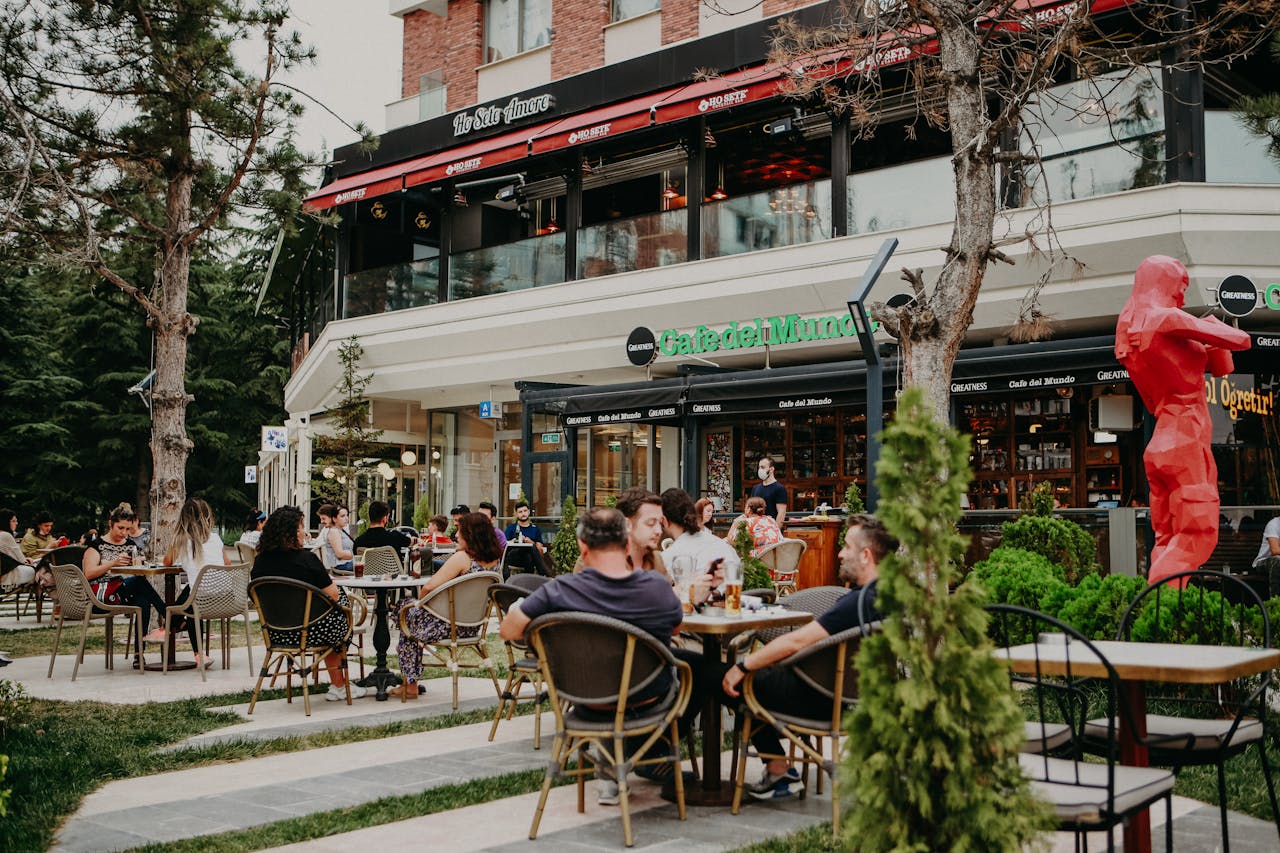 services-03 People enjoying a casual gathering at an outdoor cafe, surrounded by greenery and city atmosphere.