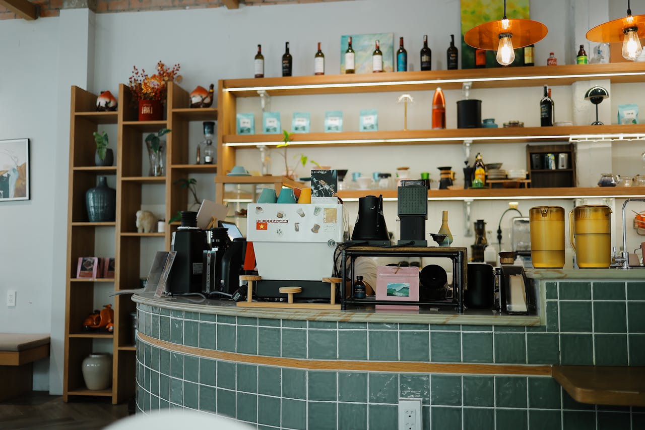 about-01 Cozy coffee shop interior featuring a green tile counter, espresso machine, and stylish decor.
